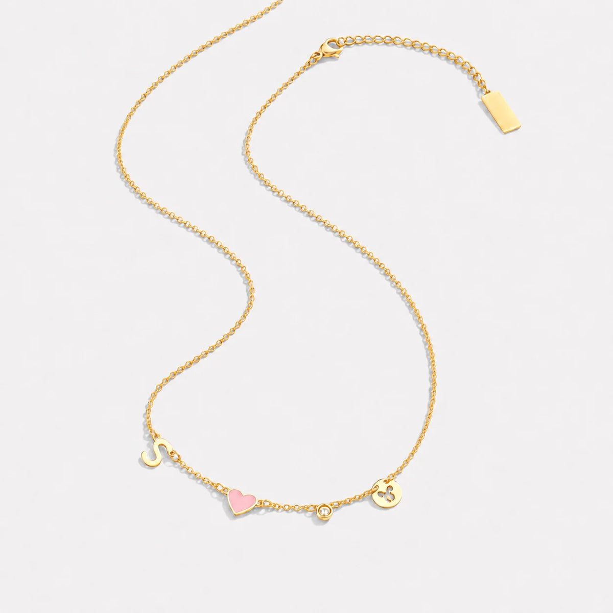 Heart initial necklace in 18K gold, flat lay