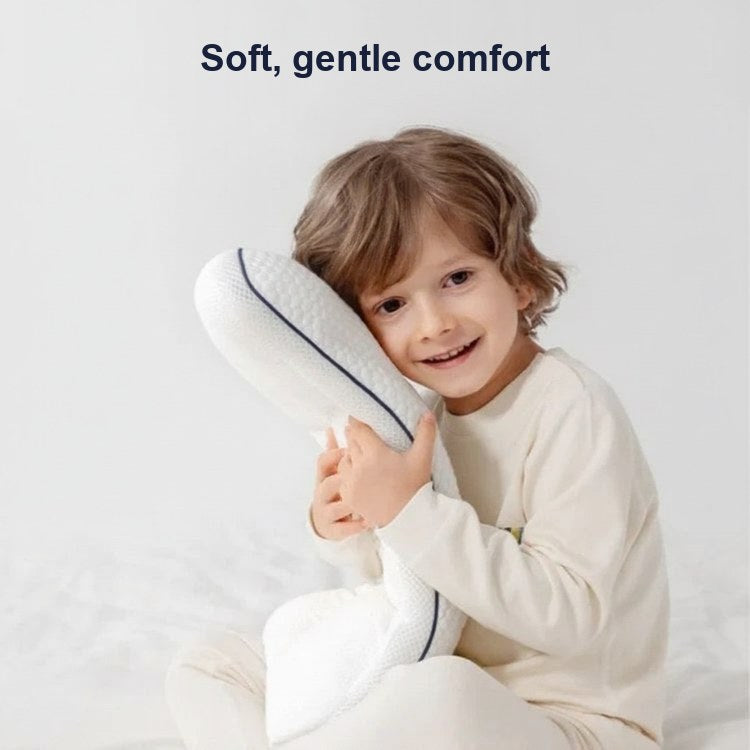 Smiling young boy sitting on a white bed hugging the pillow, captioned soft, gentle comfort.